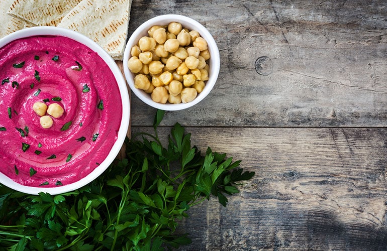 Beet hummus, pita bread and ingredients on wooden background