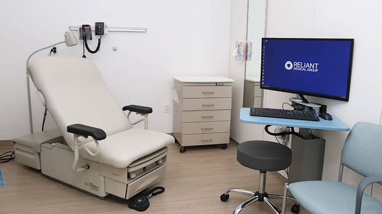 Exam room with a computer that features the Reliant logo