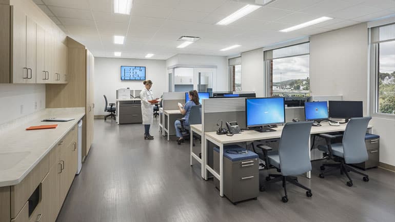Nurse sitting at computer while talking to a doctor
