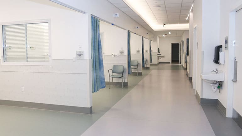 Medical hallways with multiple exam rooms separated by walls and curtains